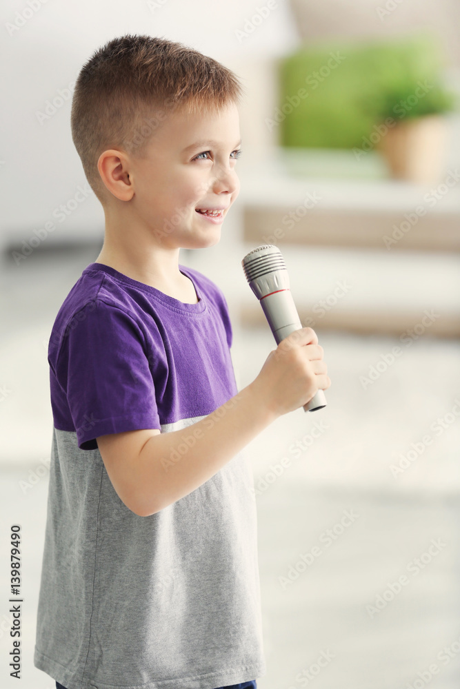 Cute little boy with microphone at home