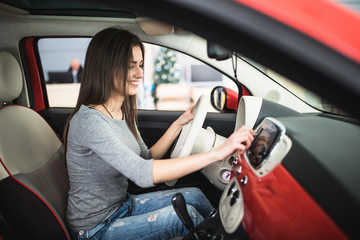 Car dashboard. Radio closeup. Woman sets up button on dashboard