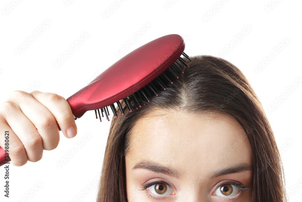 Young woman brushing hair on white background, closeup