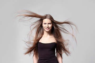 Wall Mural - Beautiful young woman with long straight hair on light background