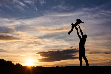 father and his daughter playing on the beach at the sunset time. Happy evening