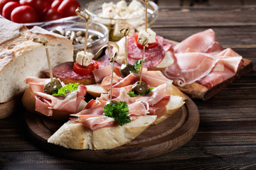 Sticker - Spanish tapas with slices jamon serrano, salami, olives and cheese cubes on a wooden table