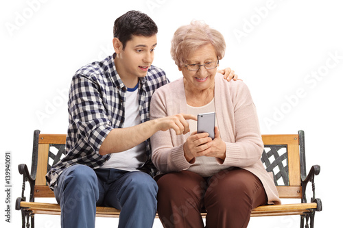 Fotografie, Obraz Young man showing elderly woman how to use mobile phone