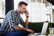 © baranq - Man at cafe talking on the phone and using his laptop