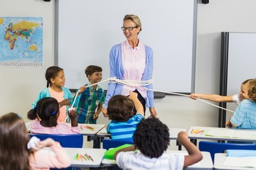 Students tying up a teacher with rope in classroom