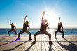 © Cookie Studio - Silhouettes of sportive girls dancing near sea at sunrise.