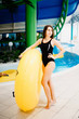 © Parilov - Girl in a black bodysuit with an inflatable ring of yellow color in the water park.