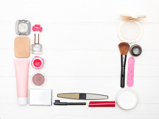 Cosmetics lying around empty space on a white wooden background