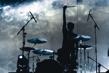 Rock Band Performs On Stage. Musician Drummer Silhouette In The Concert. Silhouette Of Drum Player In Action On Stage In Front Of Concert Crowd.
