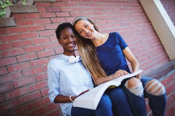 Wall Mural - Portrait of happy schoolgirls reading book