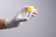 © bonnontawat - Hand with latex glove holding empty urine plastic container
