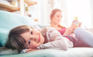 Mother and daughter sitting on sofa and reading book