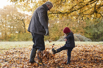 Wall Mural - Grandfather And Granddaughter Kicking Leaves On Autumn Walk