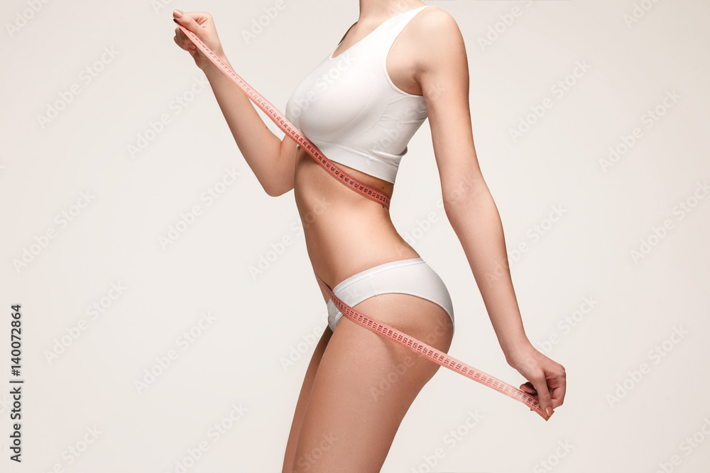 The girl taking measurements of her body, white background. - obrazy, fototapety, plakaty 