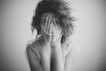 Double exposure black and white portrait of a woman covering her face and eyes with her hands 