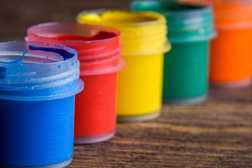  jars with colorful gouache paints on wooden background