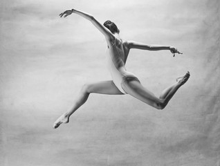 Young beautiful modern style dancer jumping on a studio background