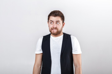 Wall Mural - portrait of handsome pensive brunette man in white shirt on gray background. guy thinks