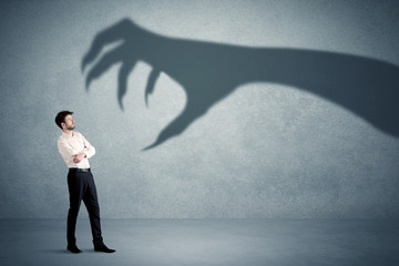 Wall Mural - Business person afraid of a big monster claw shadow concept