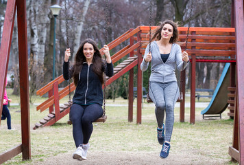 two young woman swinging in a park