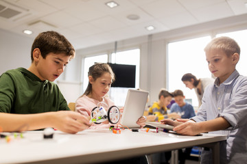 kids with tablet pc programming at robotics school