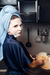 © Parilov - The girl washes the dirty dishes with a frying pan in a nourishing mask on the skin. Mask for rejuvenating and eliminating skin defects. Acne