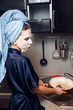 © Parilov - The girl washes the dirty dishes with a frying pan in a nourishing mask on the skin. Mask for rejuvenating and eliminating skin defects. Acne