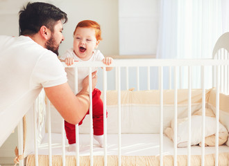 Wall Mural - happy father playing with infant baby in the cot at home
