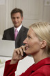 © STOCK4B  - Young blond woman is phoning in front of a man who is working with a laptop, selective focus