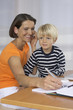 © Gudrun - Mother phoning with a mobile phone and taking notes, son (4-5 Years) sitting on her lap