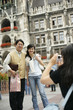 © STOCK4B  - Young Asian woman taking a picture of an Asian man and a woman in front of the town hall of Munich, selective focus