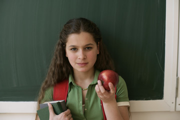 Wall Mural - Teenage girl holding an apple in front of a blackboard