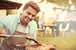 © Africa Studio - Handsome young man preparing barbecue steaks on grill
