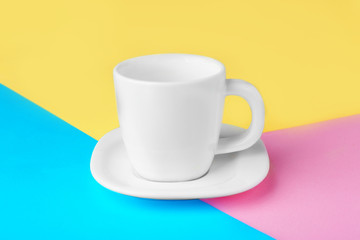 Poster - Blank ceramic cup with saucer on color paper background