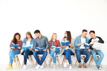 Poster - Group of people reading books while sitting near light wall