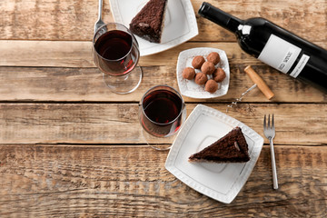 Wall Mural - Red wine, chocolate truffles and tasty cake on wooden background