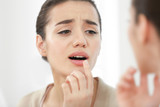 Fototapeta Do pokoju - Beautiful woman applying cream onto lips near mirror