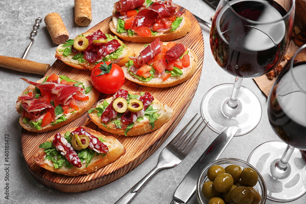 Tasty bruschetta served with wine on gray background