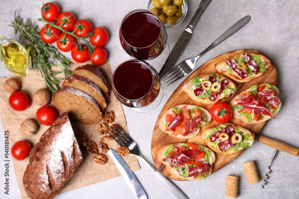 Tasty bruschetta served with wine on gray background