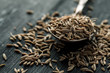 Cumin seeds in metal spoon on a wooden table, horizontal, selective focus