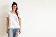 © WHstudio Leushin N - Indoor shot of stylish Caucasian young redhead woman wearing trendy black hat, white t-shirt and ragged jeans standing isolated against blank studio wall with copy space for your advertising content