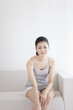 © amanaimages - Woman sitting on sofa massaging leg