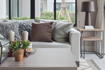 Brown and texture pillows on beige sofa with candles on wooden top table