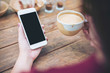 © Farknot Architect - Mockup image of white mobile phone with blank black screen and hot latte coffee on vintage wood table in cafe