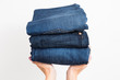 © Andrii Oleksiienko - Closeup of two caucasian female hands holding three pairs of blue denim jeans. Isolated on white background. Horizontal color photo.