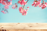 Top of wood table empty ready for your product and food display or montage with pink cherry blossom flower (sakura) on sky background in spring season. vintage color tone.