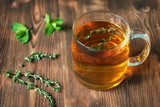 Fototapeta Zwierzęta - The Cup of tea on wooden background with mint leaves and thyme
