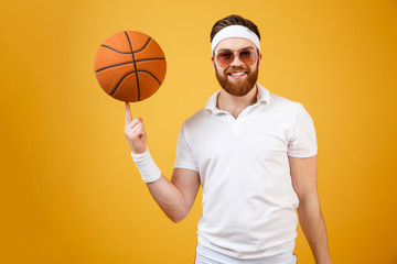 Wall Mural - Smiling sportsman in sunglasses holding basketball on finger