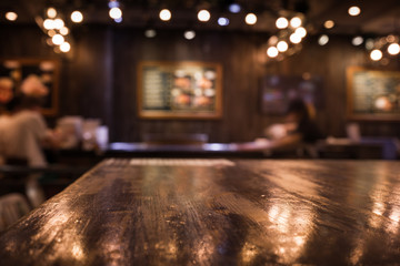 Wall Mural - Wood table top on blur cafe (restaurant) in dark night with light background/selective focus.For montage product display