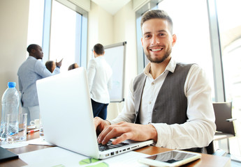 Canvas Print - Handsome businessman working with laptop in office.